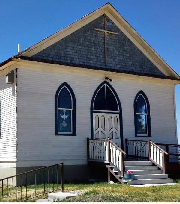 The white clapboard 1913 German Lutheran Church with blue arched windows and front steps