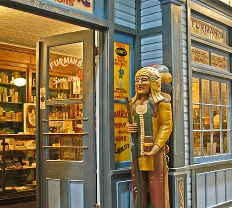 Furman’s Drug Store on Main Street, with a carved wooden figure beside the open door